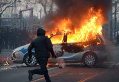 Ein Polizeiauto steht in Flammen. (Bild: Keystone)