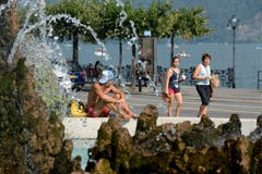 Menschen verschaffen sich Kühlung beim Brunnen fontana di Piazza Manzoni in Lugano. (Bild: Keystone)