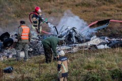 Feuerwehrleute löschen die brennenden Trümmer des Helikopters. (Bild: Keystone)
