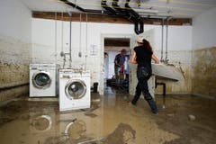 Eine Frau räumt ihre Waschküche aus, die unter Wasser steht. (Bild: Keystone)