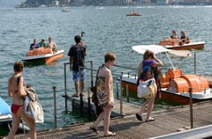 Menschen erfrischen sich an diesem heissen Sommertag mit einem Bad im See in Lugano. (Bild: Keystone)