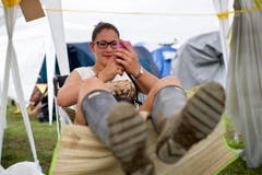 Gummistiefel für den Schlamm, kurze Hosen für die Sonne - und das Handy für die Freunde. (Bild: Keystone)