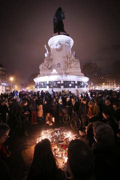 Die Menschen zünden auf den Place de la Republique in Paris Kerzen an. (Bild: Keystone)