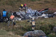 Feuerwehrleute löschen Flammen in den Trümmern des Helikopters. (Bild: Keystone)