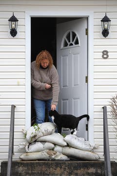Paula Bacco mit ihrer Katze Phoebe. Den Eingang zum Haus hat Bacco mit Sandsäcken verbarrikadiert. (Bild: Keystone)