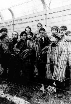 Eine Gruppe gefangener Kinder in Häftlingskleidung wartet am Tag der Befreiung von Auschwitz darauf, dass der Stacheldraht durchtrennt wird. (Bild: Keystone)