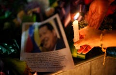 Eine Frau zündet eine Kerze für Hugo Chávez an. (Bild: Keystone)