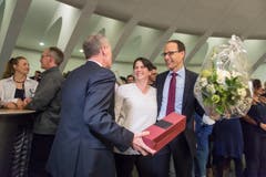 Sven Bradke (FDP) übergibt Marc Mächler ein Geschenk, daneben steht dessen Ehefrau. (Bild: Michel Canonica)