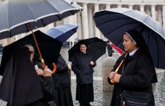 Nonnen mit Regenschirm warten im Regen auf dem Petersplatz in Rom. (Bild: Keystone)