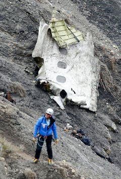 Ein Mann bei einem Wrackteil der Germanwings-Maschine. (Bild: Keystone)