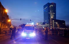 Ein Polizeibus fährt am Morgen früh an Barrikaden vorbei, um sich auf die erwarteten Demonstranten vorzubereiten. Im Hintergrund ist das beleuchtete Gebäude der Europäischen Zentralbank zu sehen. (Bild: Keystone)