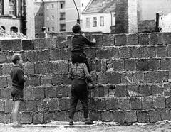 Neugierige Berliner Kinder erhaschen am 23. August 1961 über die frisch errichtete Mauer im Berliner Bezirk Wedding einen Blick nach Ostberlin. (Bild: Keystone)