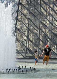 Auch in Paris - hier beim Louvre - ächzte man unter der Hitze. Und war froh um jede Abkühlung. (Bild: THOMAS PADILLA (AP))