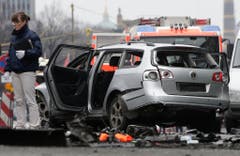 Eine Frau von der Spurensicherung steht neben dem beschädigten Auto. (Bild: Keystone)