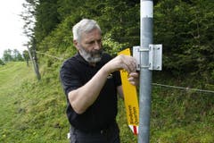 Willi Marthy montiert die Wegweiser, schiebt sie danach hoch und befestigt sie. (Bild: Jolanda Riedener)