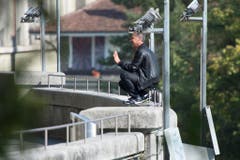 Mit einem Benzinkanister neben sich kauert der Mann auf der Brüstung. (Bild: Keystone)