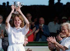 Martina Hingis zeigt am 3. Juli 1994 die Trophäe, die sie soeben von der Herzogin von Kent, rechts, in Empfang nehmen durfte. Das Ausnahmetalent ist die jüngste Gewinnerin des Juniorinnen-Titels in Wimbledon. (Bild: Keystone)
