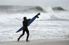 Während mehrere Ortschaften an der Ostküste bereits evakuiert worden sind, geniesst ein Surfer in Long Beach die hohen Wellen. (Bild: Keystone)