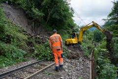 Bei Les Avants befreit schweres Gerät die Schienen der Montreux-Zweisimmen-Bahn (MOB) von Bäumen und Erdreich. (Bild: Keystone)