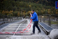 Marcello Crüzer vom Bauamt der Gemeinde Bregaglia öffnet das Absperrband über die Notbrücke, die nach Bondo führt. (Bild: KEYSTONE/Gian Ehrenzeller)