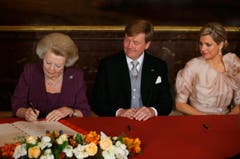 Jetzt ist sie nicht mehr Königin: Beatrix unterschreibt die Abdankungsurkunde. Neben ihr sitzen der neue König Willem-Alexander und Königin Maxima. (Bild: Keystone)