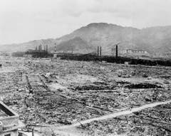 Hier standen früher Industriebauten und kleinere Wohnhäuser. Nach dem Atombombenabwurf sieht man nur noch die Überreste der Mitsubishi Waffenfabrik und ein mit Beton verstärktes Schulgebäude am Bergfuss. (Bild: Keystone)