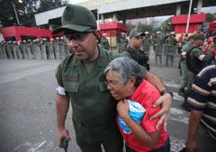 Ein Armeeangehöriger tröstet vor dem Militärspital in Caracas eine Frau. (Bild: Keystone)