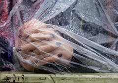 Eine Frau mit Regenschutz betet auf dem Petersplatz. (Bild: Keystone)