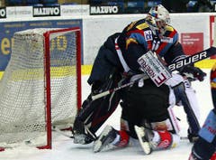Kloten Flyers Torhüter Ronnie Rüeger, links, wird von Zugs Verteidiger Andy Wozniewski umgefahren.