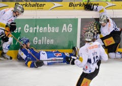 Die Zuger Dario Bürgler, Fabian Sutter und Fabian Schnyder (von links) kümmern sich um den am Boden liegenden Davoser Beat Forster. (Bild: Keystone)