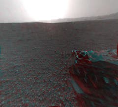 Auch hinter dem Rover ist die Landschaft karg. In der Distanz lässt sich auch hier wieder der Rand des«Gale»-Kraters erkennen. Im Vordergrund ist eines der sechs Räder von«Curiosity» zu sehen. Die 3D-Stereo-Aufnahme ist wegen des Sonnenscheins leichtüberbelichtet. (Bild: Nasa / JPL-Caltech)
