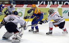 Der Kloten Flyers-Stürmer Denis Hollenstein vor dem Tor des EV Zug. Links Torhüter Sandro Zurkirchen, rechts Verteidiger Alessandro Chiesa.