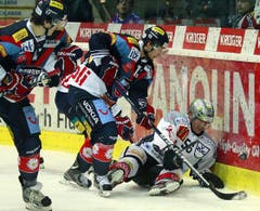 Zugs Verteidiger Timo Helbling, am Boden, gegen Kloten Flyers Stürmer Simon Bodenmann, Mitte, und Stürmer Arnaud Jacquemet.