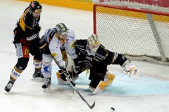 Luganos Alessandro Chiesa, links, Zugs Emanuel Peter, Mitte, und Luganos Goalie Elvis Merzlikins, rechts, kämpfen um den Puck. (Bild: Keystone Samuel Golay)