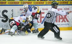 Joel Vermin und Byron Ritchie vom SC Bern bearbeiten Santeri Alatalo vom EV Zug vor den Augen von Linesman Roman Kaderli. (Bild: Keystone)