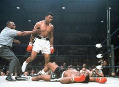Muhammad Ali (links) wird von Schiedsrichter Joe Walcott zurückgehalten. Schwergewichtsweltmeister Muhammad Ali schlug im Ring 1965 Herausforderer Sonny Liston in der ersten Runde im Titelkampf in Lewiston in Maine k.o. (Bild: Keystone)