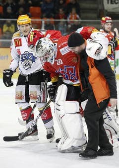 Biels Goalie Reto Berra wird verletzt vom Eis begleitet.