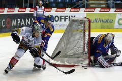 Der Zug Stürmer Reto Suri im Zweikampf gegen Kloten Flyers Verteidiger Philippe Schelling. Rechts Torhüter Ronnie Rüeger.