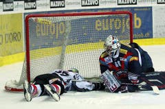 Kloten Flyers Torhüter Ronnie Rüeger, links, wird von Zugs Verteidiger Andy Wozniewski umgefahren.