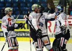 Die EV Zug-Verteidiger Samuel Erni, links, und Patrick Fischer bedanken sich bei Torhüter Sandro Zurkirchen nach dem Sieg.