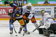 Der Zuger Stürmer Josh Holden, links, im Spiel gegen Luganos Verteidiger Clarence Kparghai, Mitte, und der Lugano Goalie Daniel Manzato. (Bild: Keystone/Alexandra Wey)