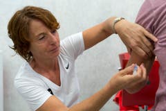 Kerstin Warnke, Chief Medical Officer Swiss Olympic, impft einen Athleten. (Bild: Keystone / Georgios Kefalas)