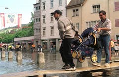 Zahlreiche Schaulustige sind nach Rorschach gekommen, um das Hochwasser zu sehen. Die Strasse können sie nur über einer Holzbrücke überqueren. (Bild: Keystone)