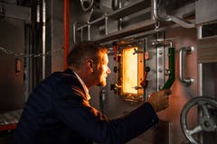 Renergia-Geschäftsleiter Ruedi Kummer blickt durch ein Fenster in den Ofen. (Bild: Roger Grütter / Perlen, 28. Mai 2018)