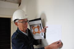 Roland Heini vor der Wand im künftigen Foyer des Dachgeschosses mit einem Entwurf des Gipsreliefs, das er darauf anbringen wird.