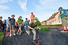 Die ersten Schulkinder testen mit Kickboard und ausgerüstet mit Helm den neuen Pumptrack.