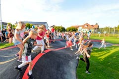 Die Kinder versammeln sich rund um die Pumptrack-Anlage.