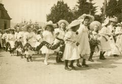 Eine frühe Foto-Ansichtskarte des Kinderfest. Das Bild ist um 1900 gelaufen und zeigt ganz in weisse Spitzen gekleidete Blumenmädchen im Anstieg zur Festwiese.