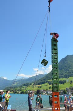 Die Leiter der Pfadi Buochs sichern Gaétan und seilen ihm Harassen zu, während er seinen Turm baut.