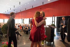 Carole Waldvogel (links ) und Aline Pironato (zweitbeste und beste Matura) umarmen sich.Links freut sich Jan Wallimann (drittbeste Matura).